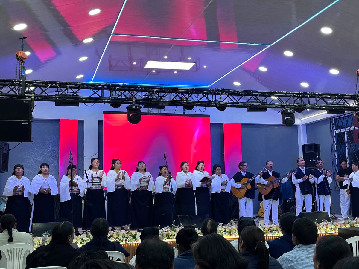 Coro folclórico presentándose en escenario con pantalla LED de fondo